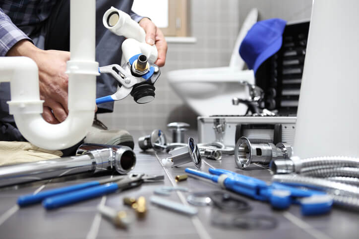 Plumbing technician fixes sink pipe in bathroom