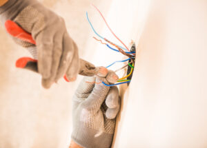 man in glovers using pliers working with electrical wires